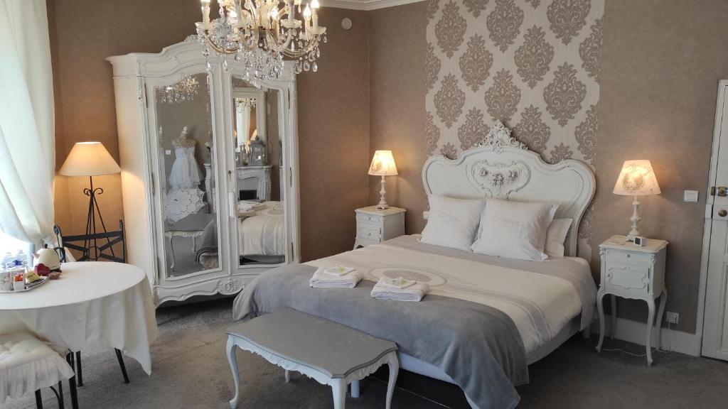 a bedroom with a large white bed and mirrors at La Clef Dort in Beauchamps