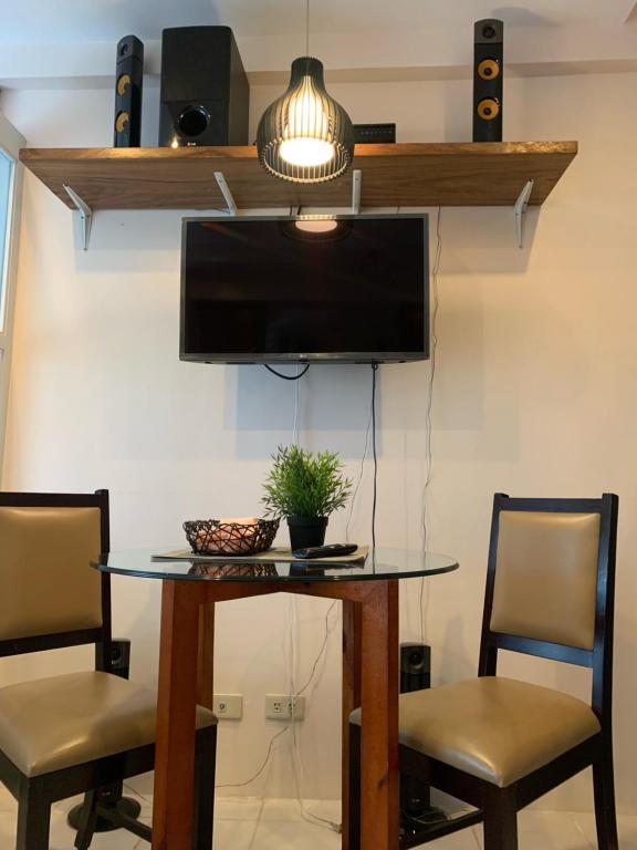 a dining room table with two chairs and a tv at Tagaytay Prime Residence -Cityland in Tagaytay