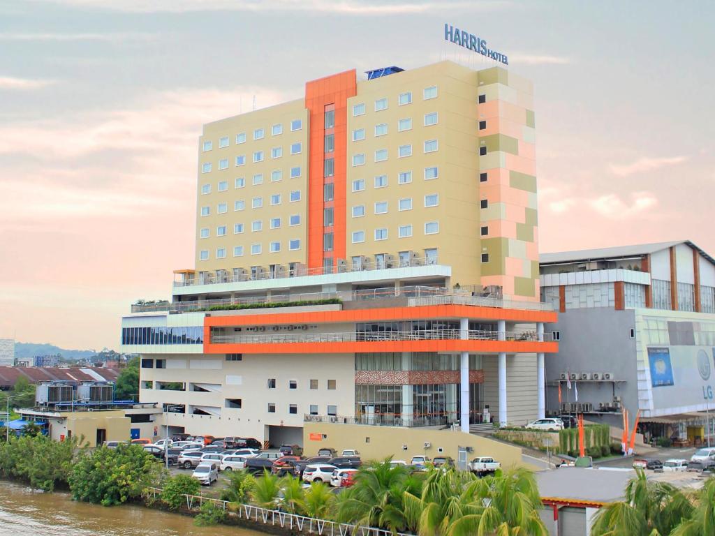 een hotelgebouw met een parkeerplaats ervoor bij HARRIS Hotel Samarinda in Samarinda