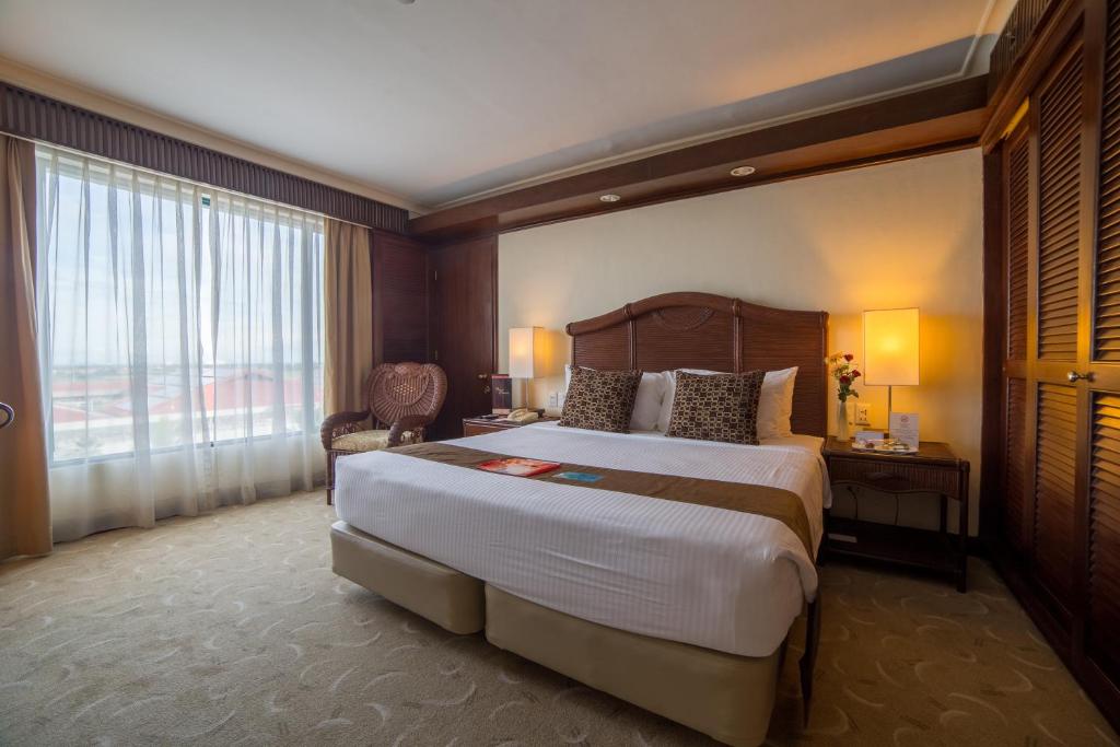 a bedroom with a large bed and a large window at Waterfront Airport Hotel and Casino in Mactan