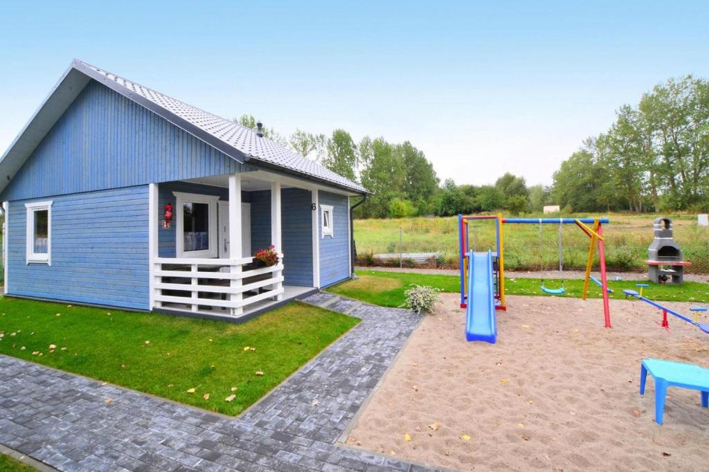 una pequeña casa azul con parque infantil en el patio en Comfortable holiday home for 4 people Ustronie Morskie en Ustronie Morskie