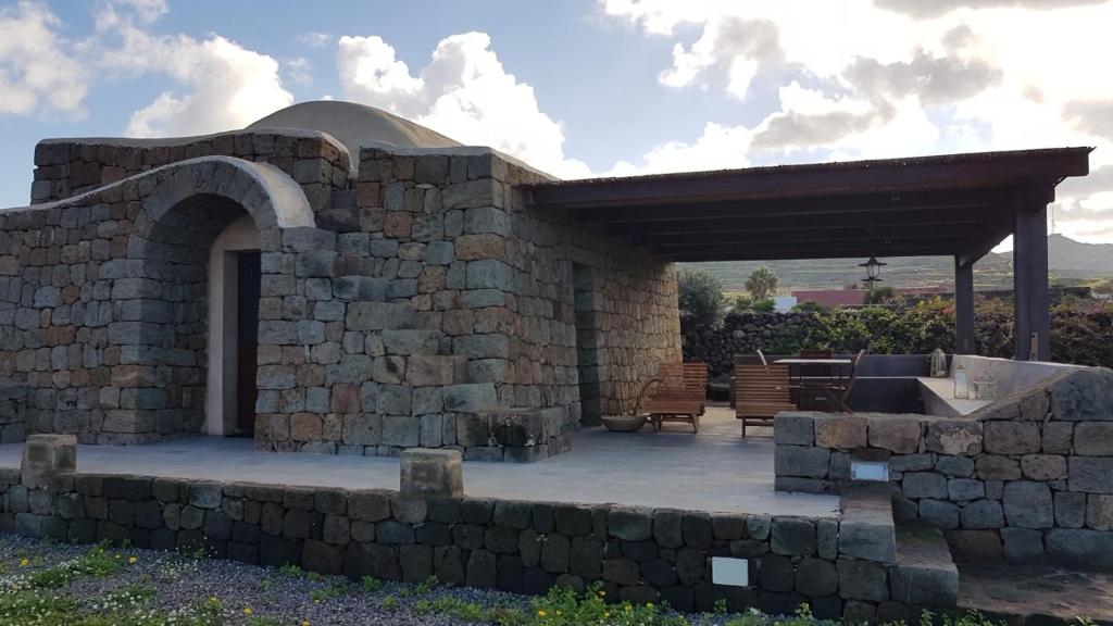 a stone walled patio with a stone fireplace and a pavilion at IL VIGNETO in Pantelleria