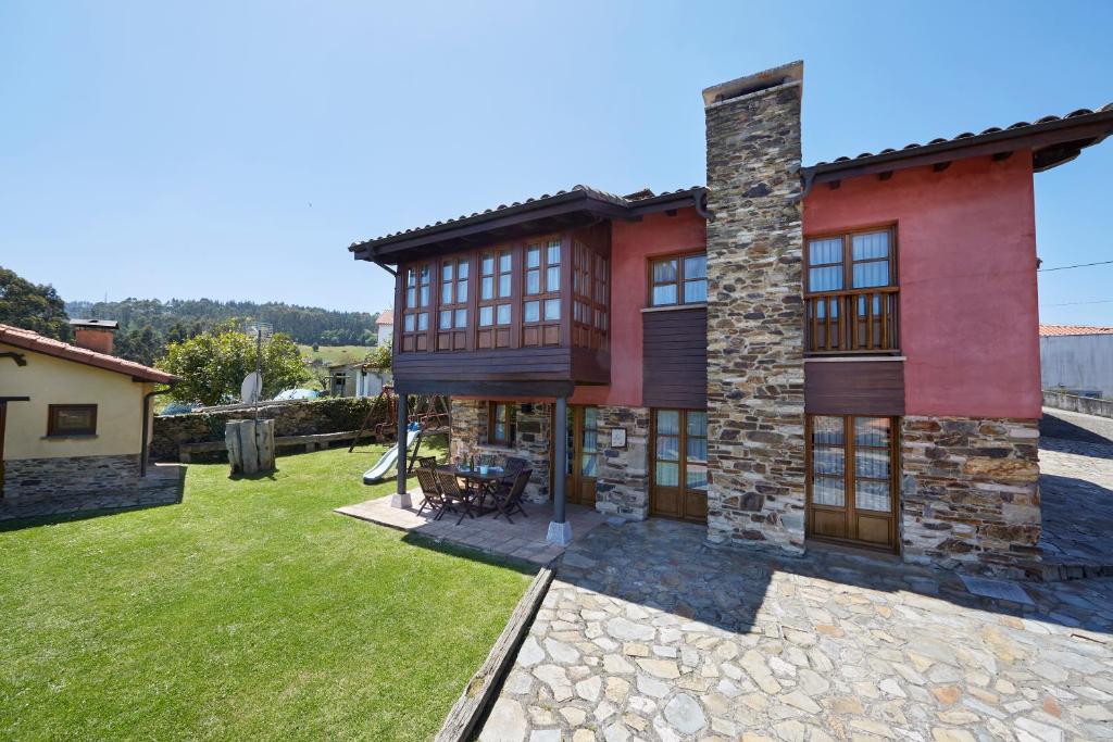 un gran edificio rojo con un patio de césped en La Quintana de Somao, Casa de Abajo en Somado