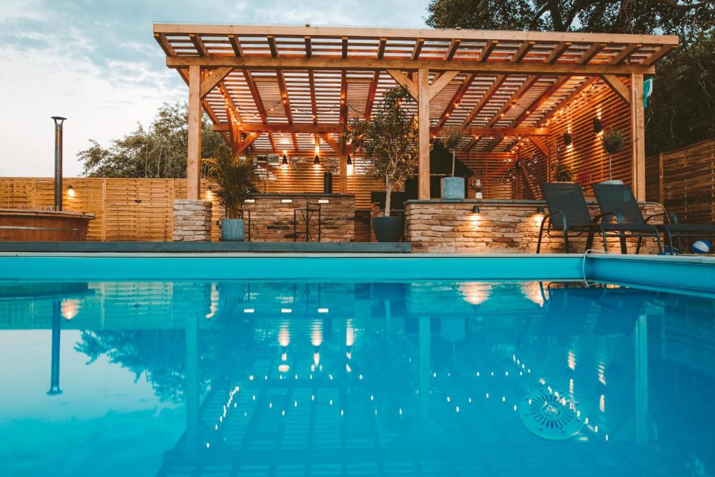 a pool with a wooden pergola and a swimming pool at Vila Casa din gradina in Voivodeni