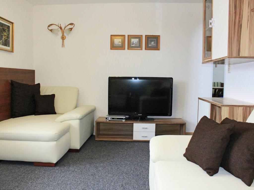 a living room with two white couches and a flat screen tv at Spacious Holiday Home in Kappl with Terrace in Kappl