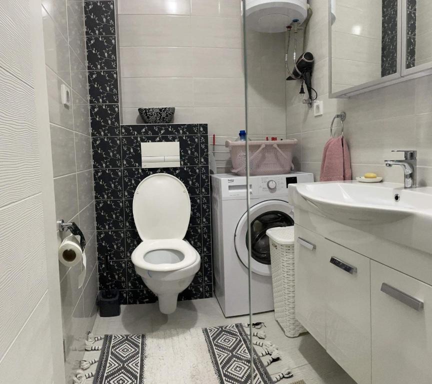 a bathroom with a toilet and a washing machine at Apartman SIMS in Bijeljina