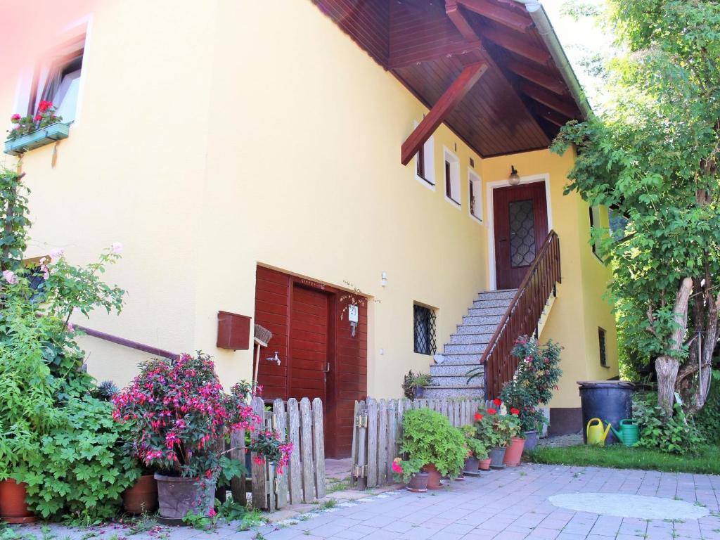 ein weißes Haus mit einer roten Tür und ein paar Blumen in der Unterkunft Apartment in Koettmannsdorf near bathing lake in Wurdach