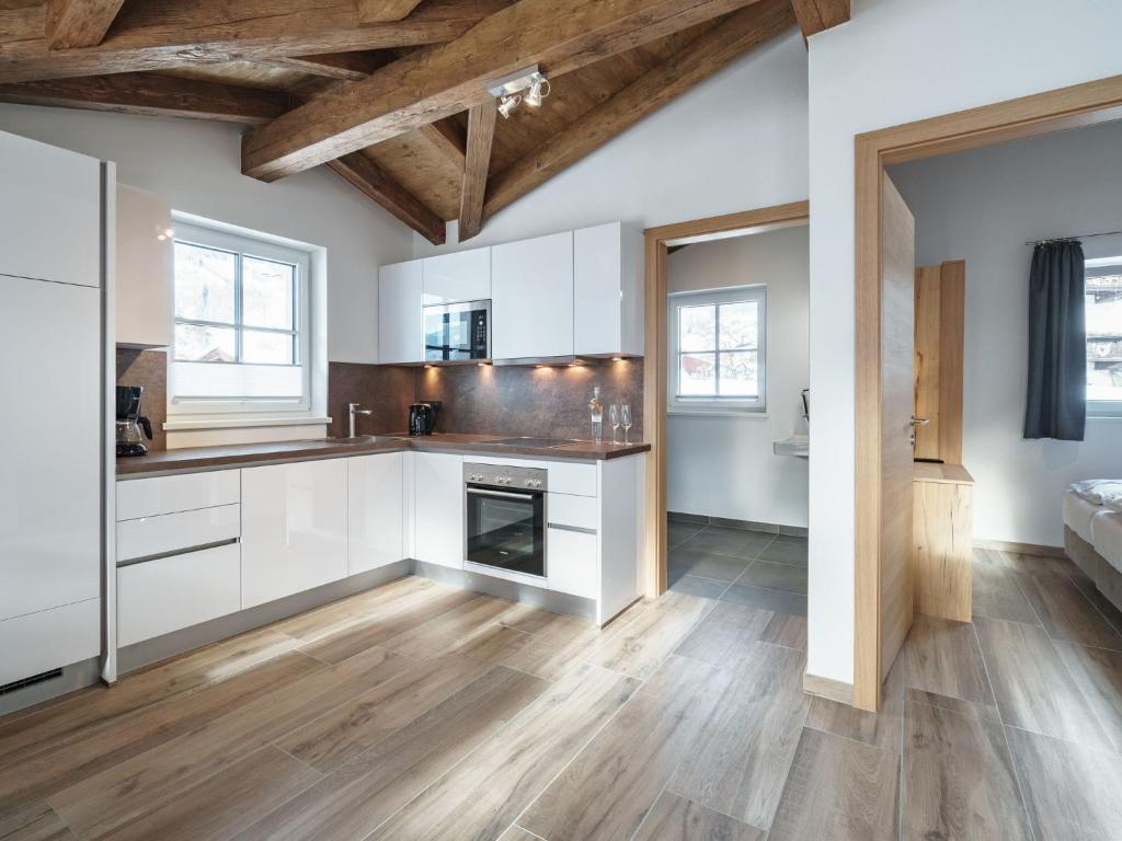a kitchen with white cabinets and wood floors at Sunny holiday home with sauna in Piesendorf in Piesendorf