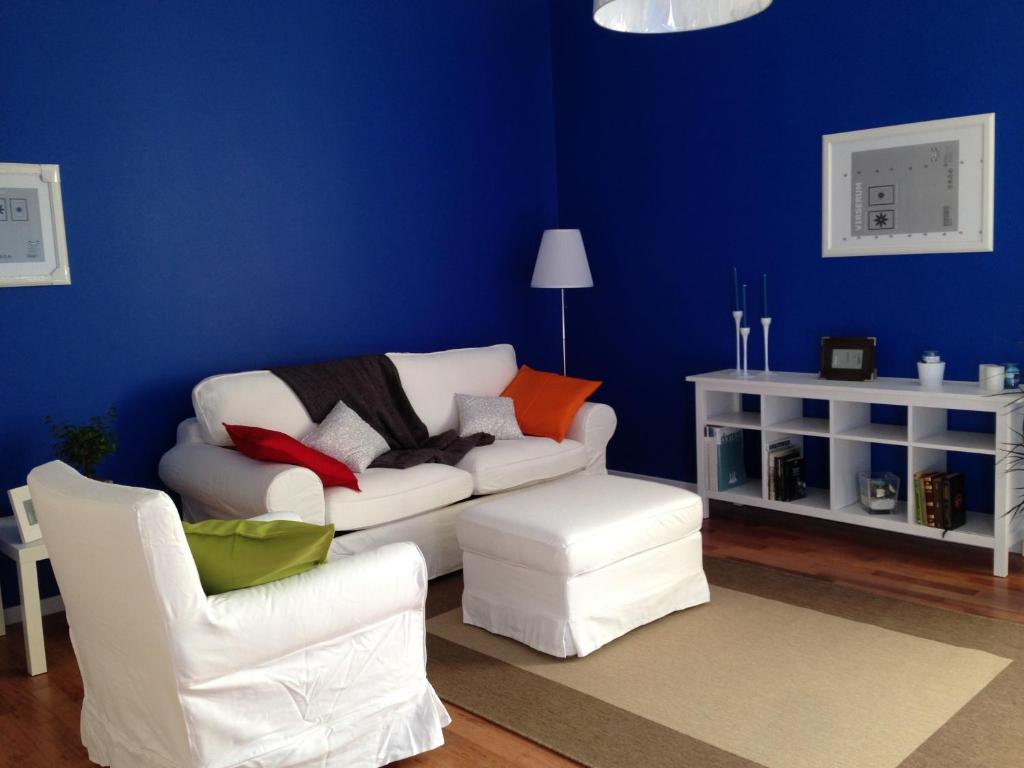 una sala de estar azul con un sofá blanco y sillas en Casa Luthi, en Siracusa