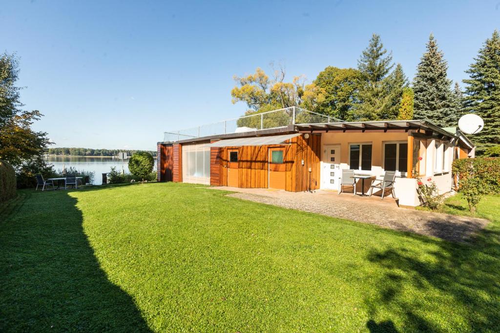 a small cabin with a large yard in front of a lake at Ferienhaus Annerose in Wendisch Rietz