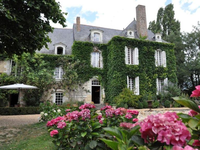 an ivy covered building with flowers in front of it at La Marronniere in Cheffes-sur-Sarthe