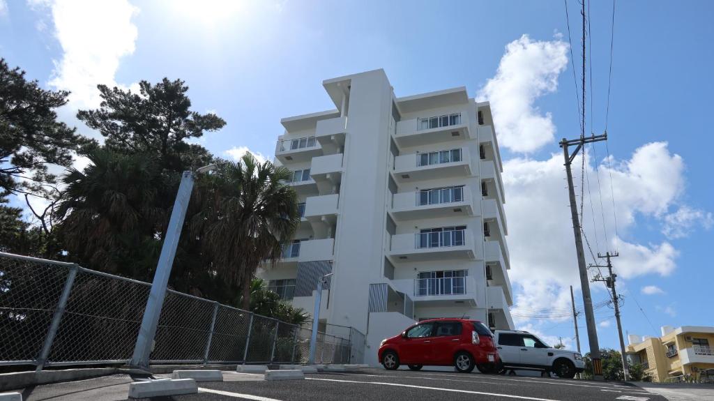 a red car parked in front of a white building at AP YOURS　Hotel４０１ in Okinawa City