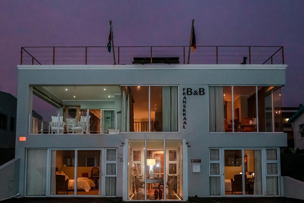 a large white house with a balcony at night at Franskraal B&B in Gansbaai