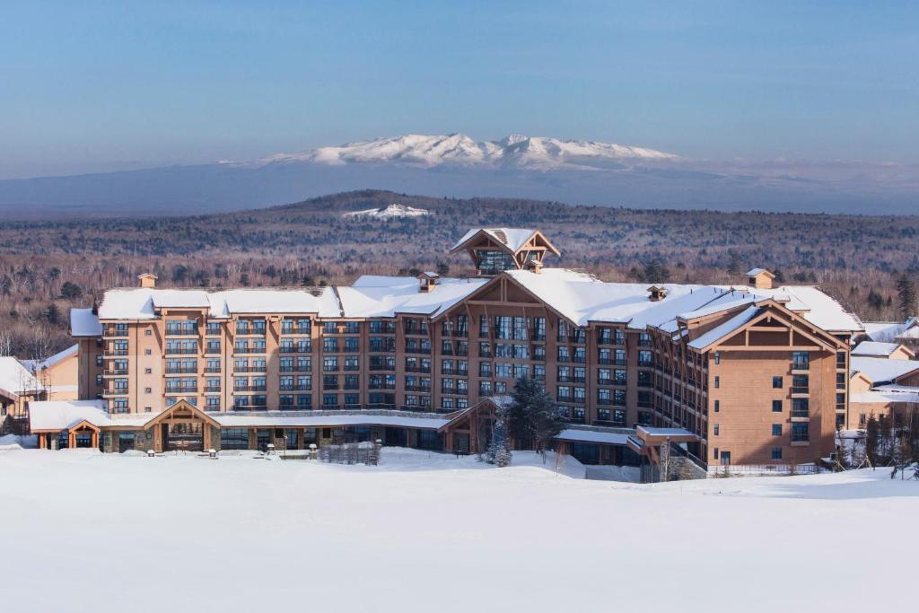 un hotel en la nieve con una montaña en el fondo en Wanda Jin Resort Changbaishan, en Baishan