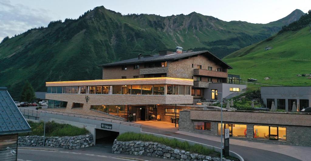 a large building with a mountain in the background at Alpenresort Walsertal in Damuls