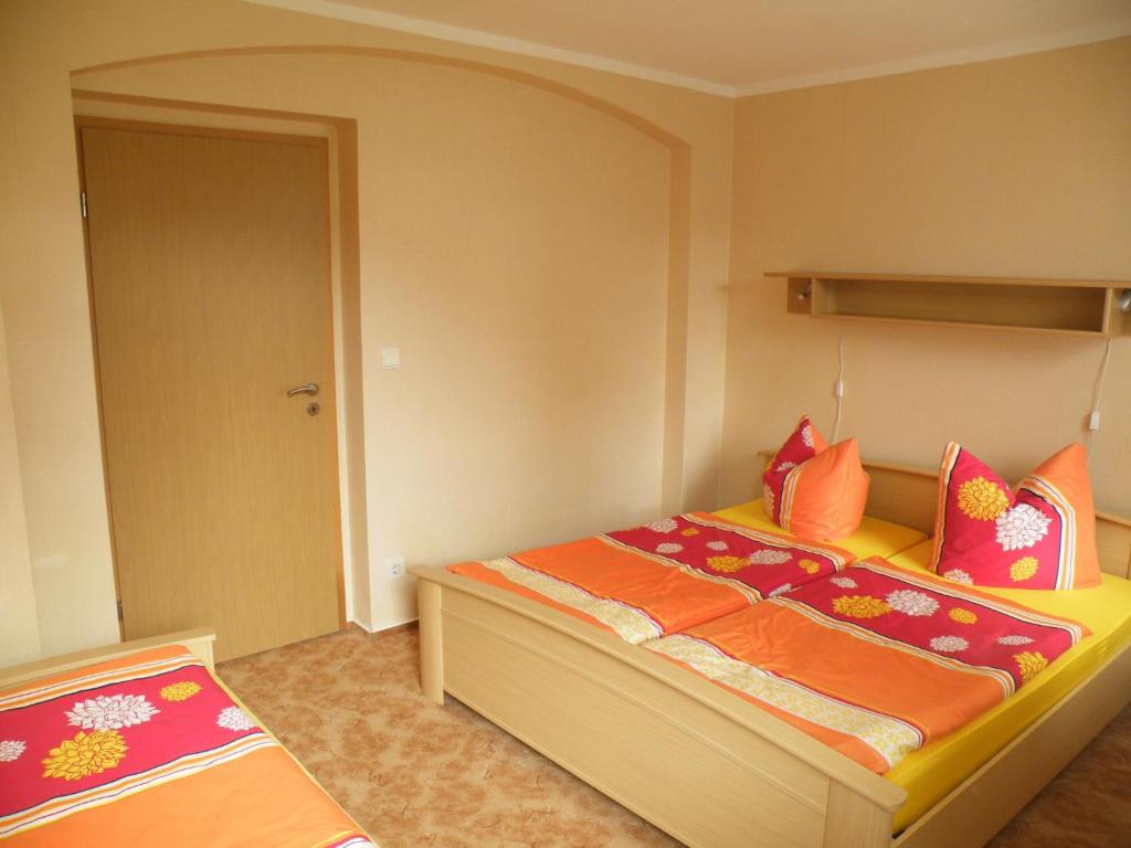 una camera da letto con un letto con lenzuola arancioni e arancioni di Am Lindenbaum a Kirnitzschtal