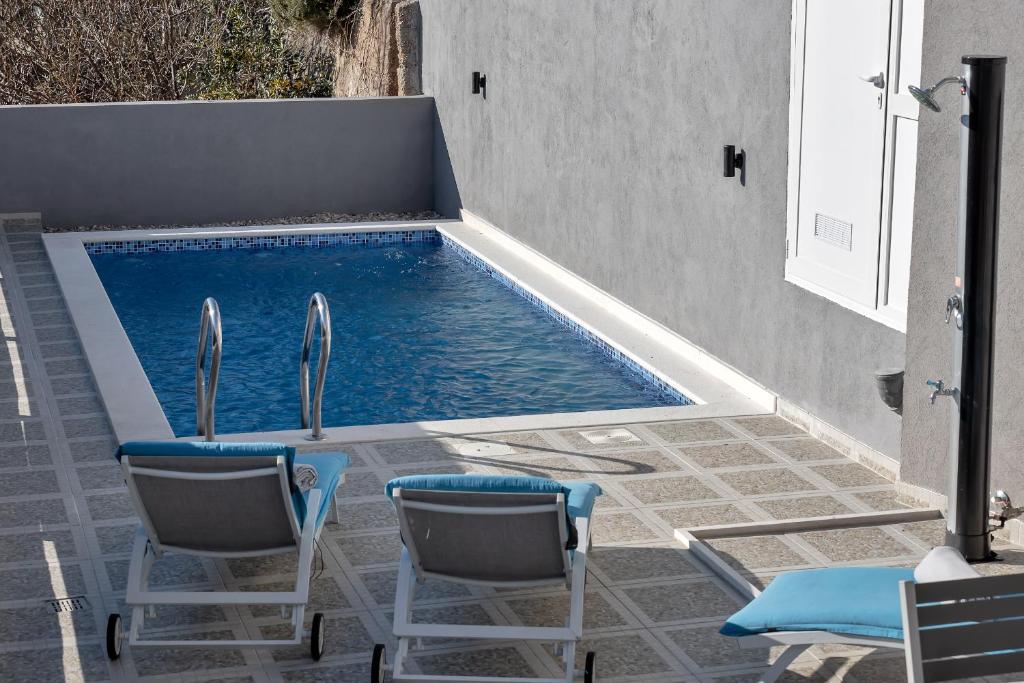 a swimming pool with two chairs and a table at Apartment Lotte with private pool in the city center! in Makarska