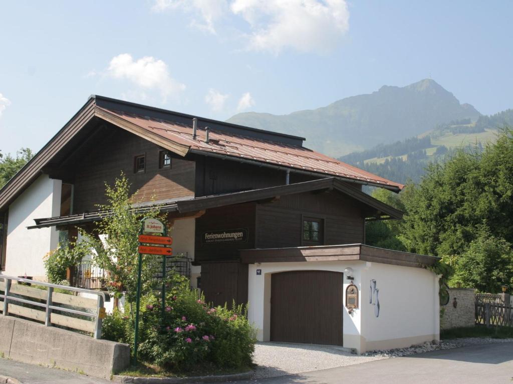 uma casa castanha e branca com garagem em Apartment in St Johann in Tyrol with a garden em Sankt Johann in Tirol