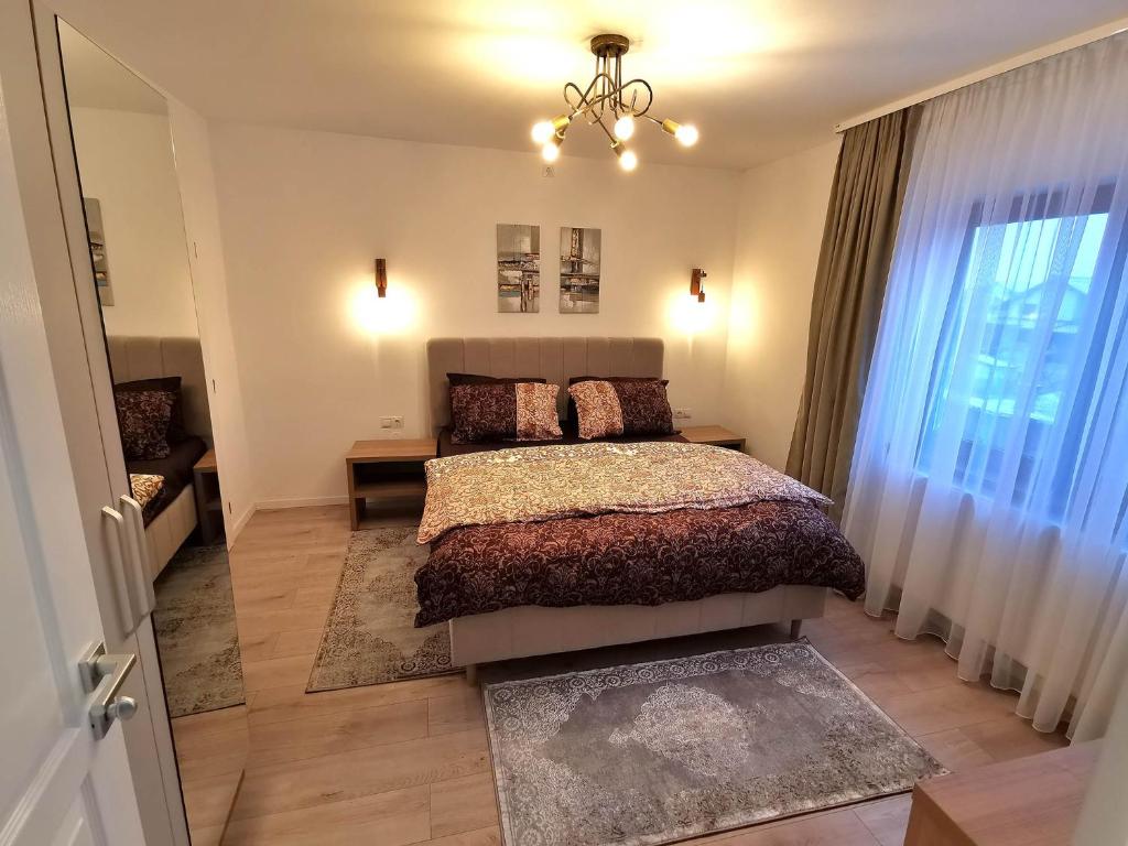 a bedroom with a bed and a chandelier at Vila Aras in Simeria