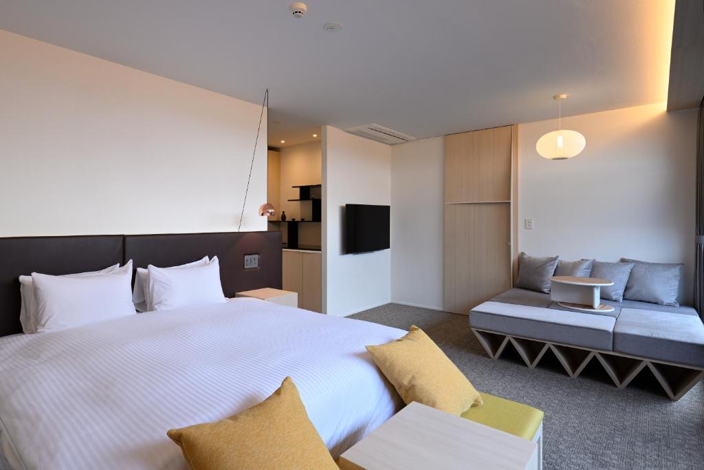 京都市にあるHOTEL KYOTOLOGYの大きなベッドとソファが備わるホテルルームです。