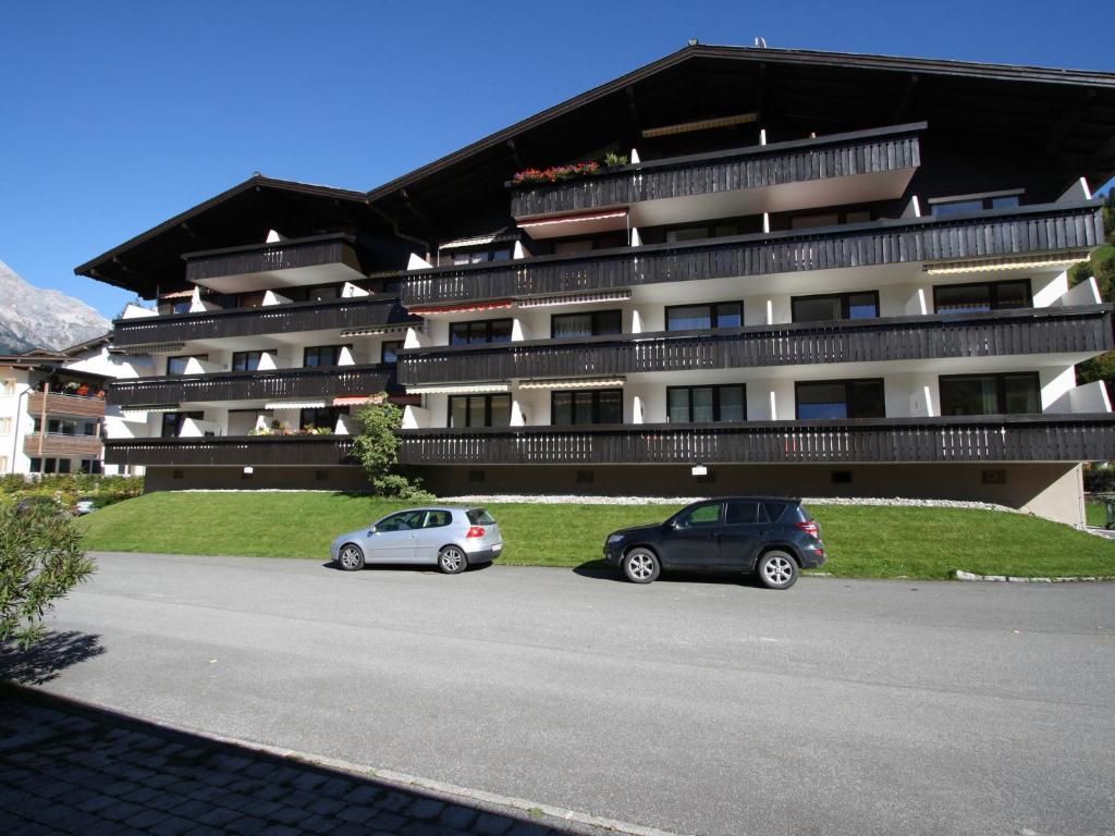 dos autos estacionados en un estacionamiento frente a un edificio en Apartment in Maria Alm directly on the ski slopes, en Maria Alm am Steinernen Meer