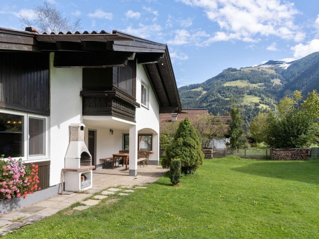 une maison blanche avec une terrasse couverte et une pelouse dans l'établissement Spacious Chalet in Maishofen near Forest, à Maishofen