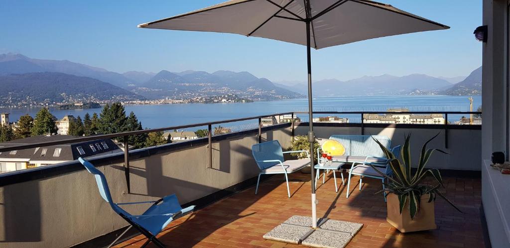 uma varanda com cadeiras, uma mesa e um guarda-sol em Terrace Lake View em Stresa