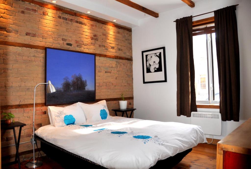 sypialnia z dużym łóżkiem z ceglaną ścianą w obiekcie Le Tierra del Fuego by HomeInMontreal w Montrealu