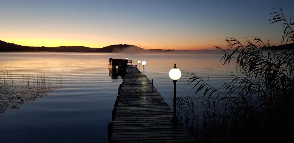 a dock with lights in the water at sunset at Kairos on the Lake in Sedgefield