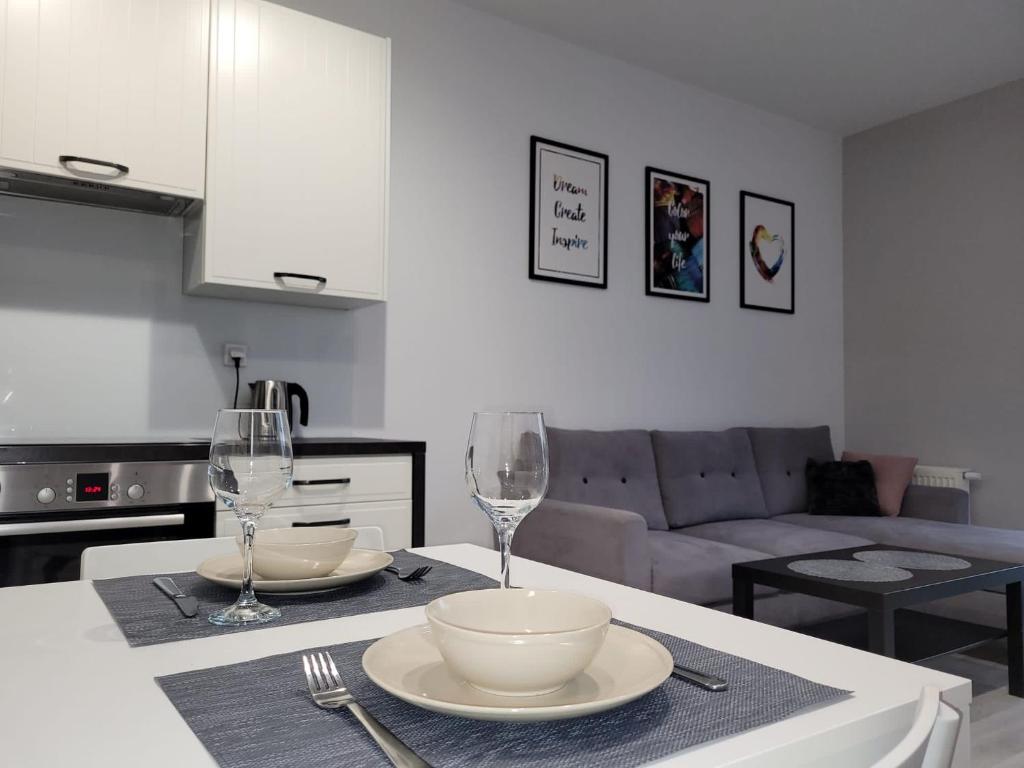 ein Wohnzimmer mit einem Tisch mit Schalen und Weingläsern in der Unterkunft Apartament Piątka in Płock