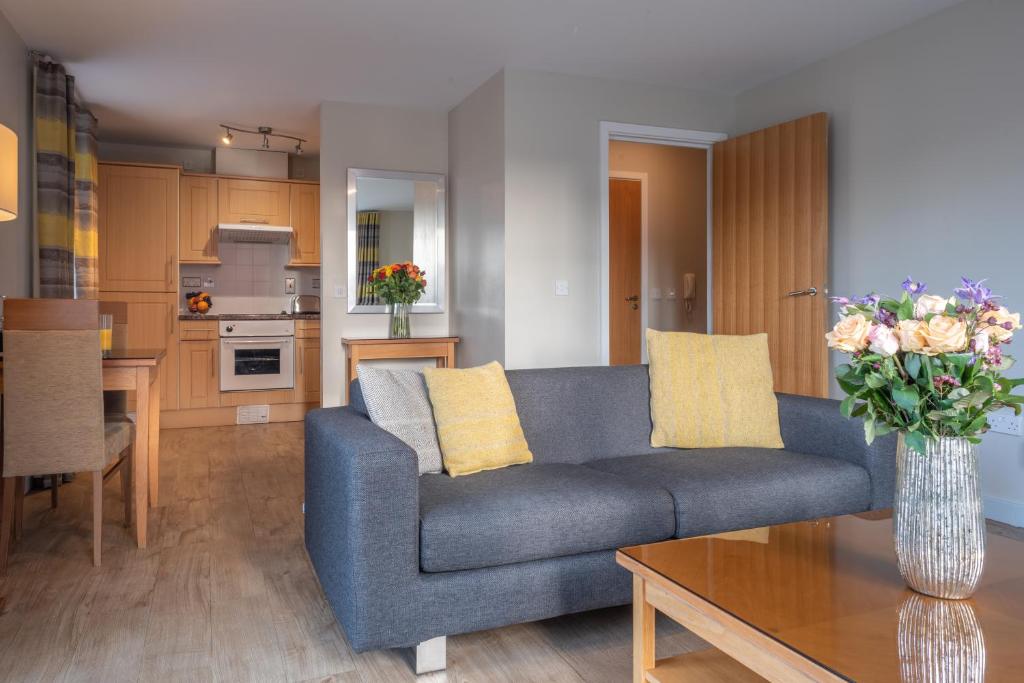 a living room with a blue couch and a vase of flowers at PREMIER SUITES Birmingham in Birmingham