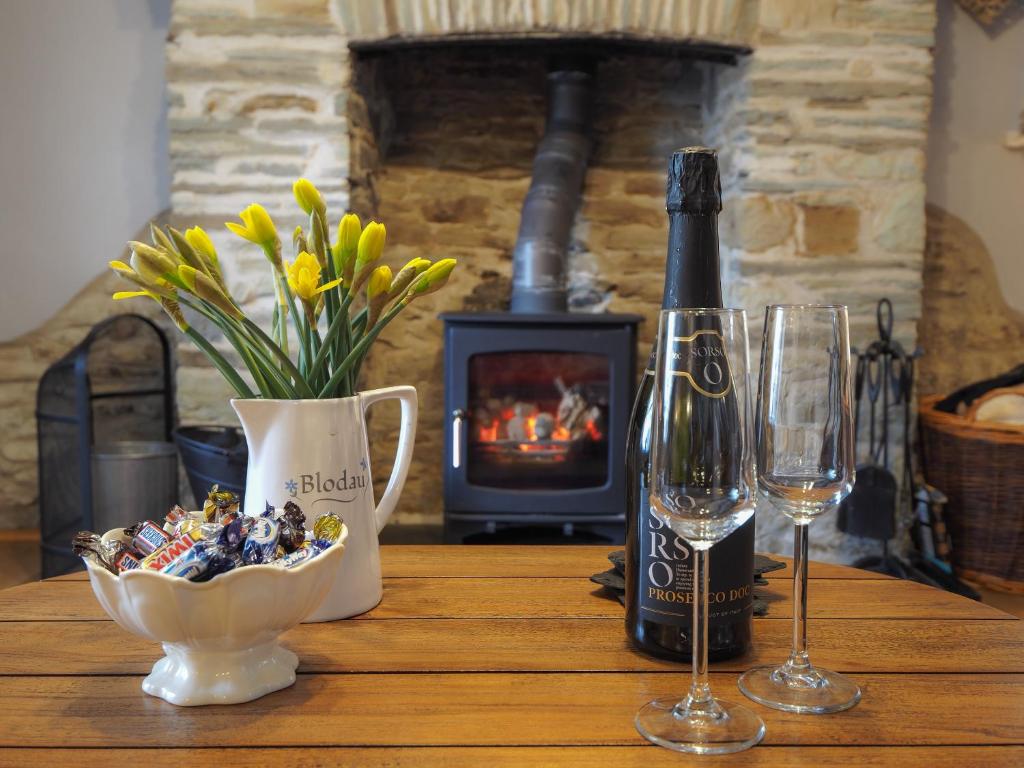 una mesa de madera con una botella de vino y una copa en Y Bwthyn en Tal-gareg