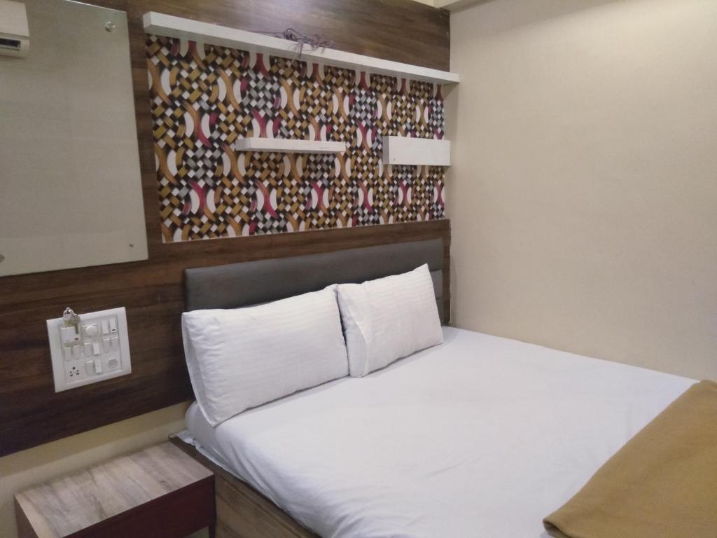 a small bedroom with a white bed and a wall at Soni Punjab Guest House in Navi Mumbai