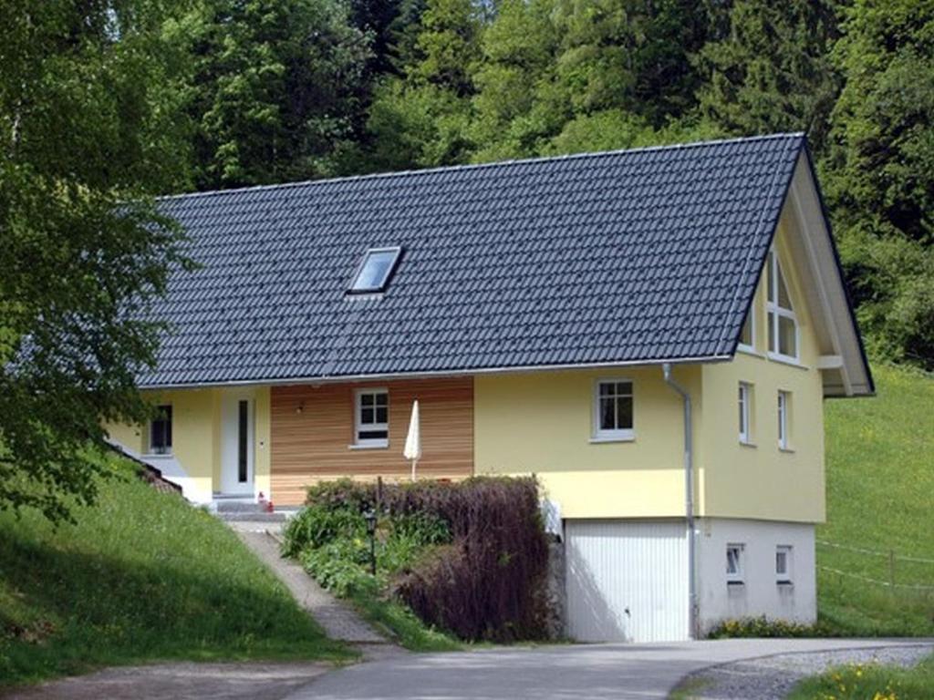 une maison jaune avec un toit noir dans l'établissement Landeckhof, à Oberwolfach