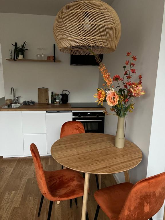 a kitchen with a table with chairs and a vase with flowers at Northgo apartment in Noordwijk