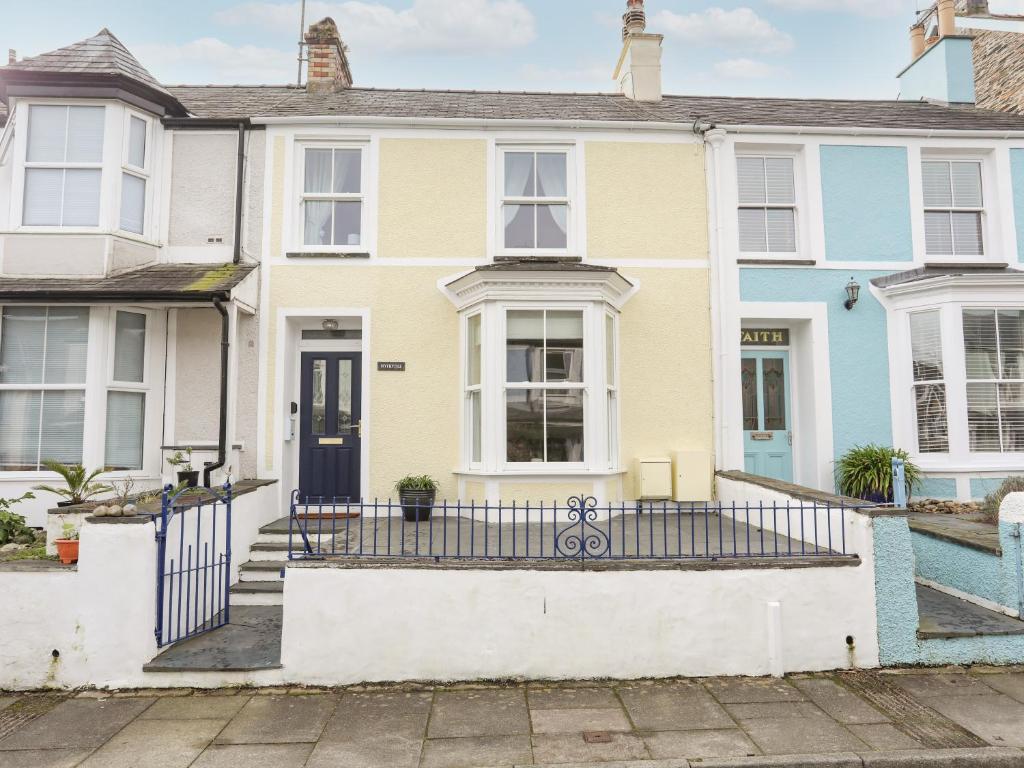 een groot geel huis met een blauwe deur bij Hyfrydle in Porthmadog