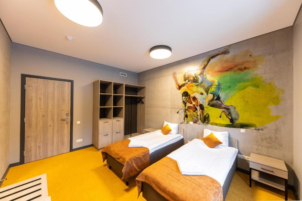 twee bedden in een kamer met een schilderij aan de muur bij Stadium Hotel in Valmiera