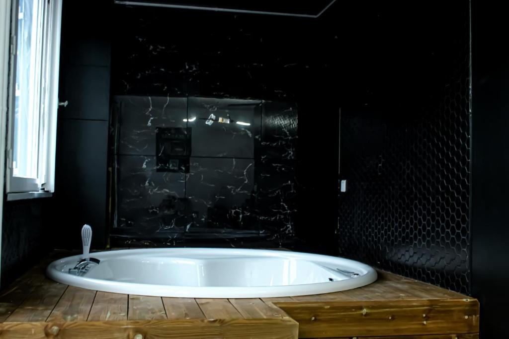 La salle de bains est pourvue d'une baignoire et d'un mur noir. dans l'établissement Seasides Paris - Suite Monroe, au Blanc-Mesnil