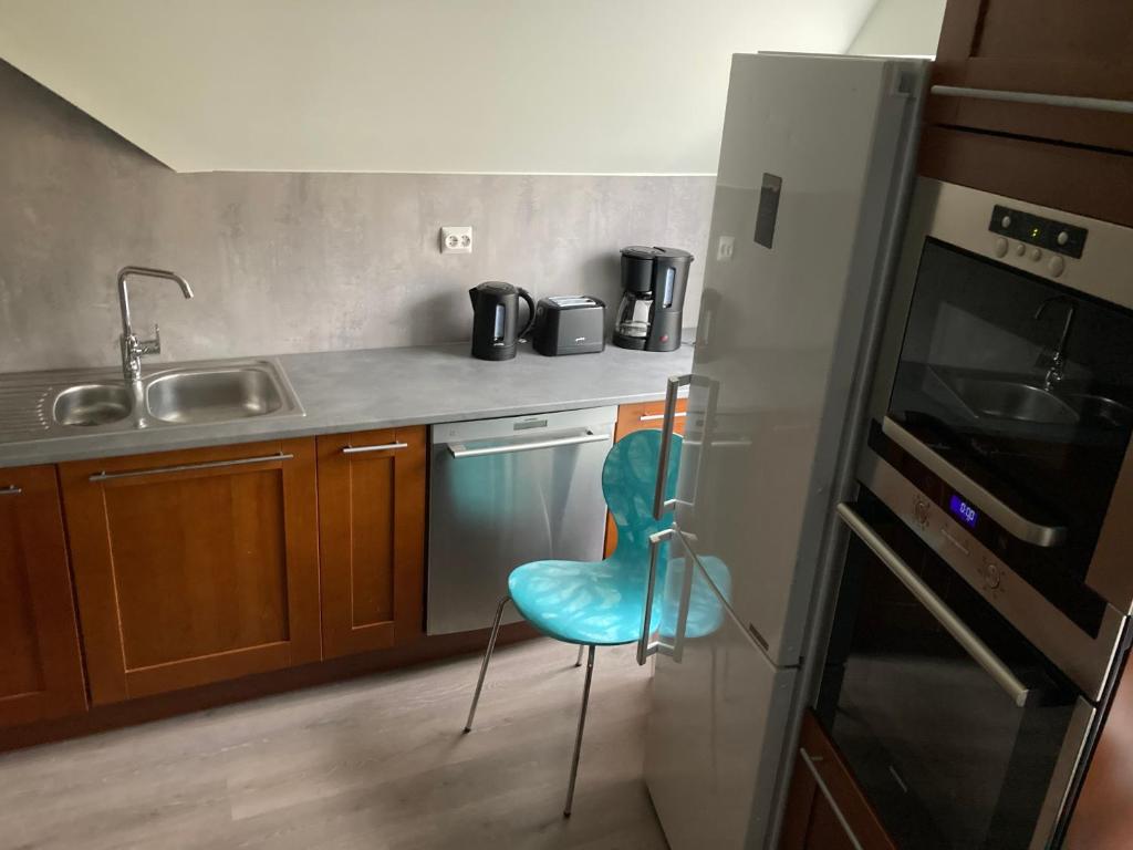 a kitchen with a blue chair in a kitchen at Downtown Historical House with Renovated apartments in Ålesund