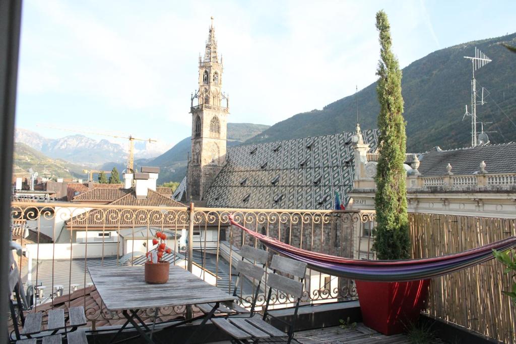 a balcony with a hammock and a church at Rosengarten Rooftop in Bolzano