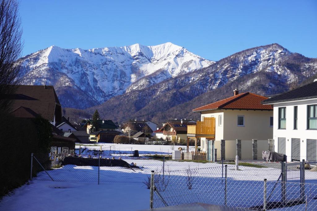 una montaña cubierta de nieve en el fondo de una ciudad con casas en Gartenappartement Leonsberg, en Bad Ischl