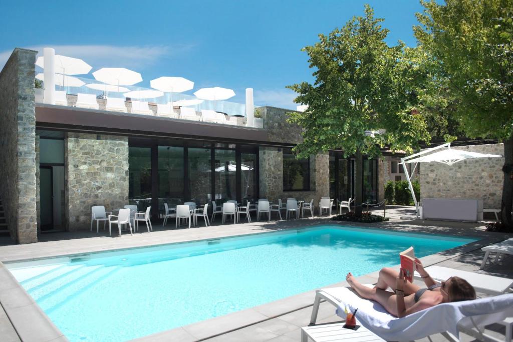 a woman laying in a chair reading a book next to a swimming pool at Isola Verde Resort in Castiglione del Lago