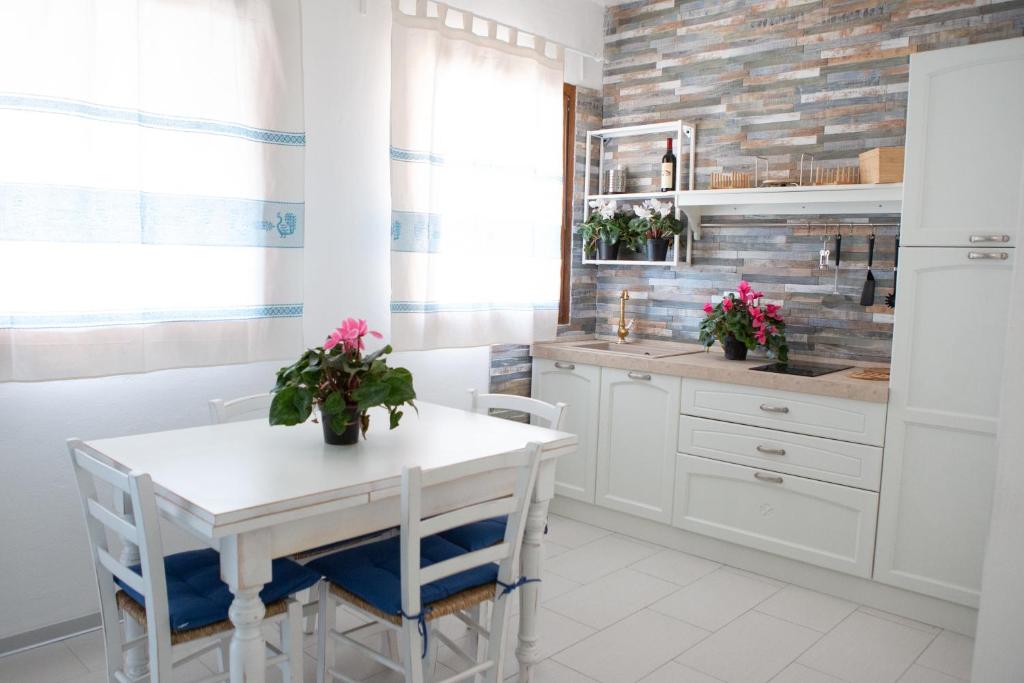 cocina blanca con mesa blanca y sillas en Bellavista, en SantʼAndrea