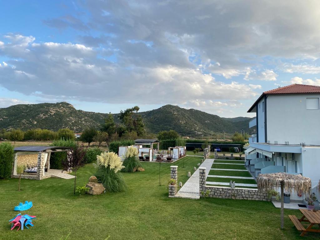 a yard with a building and mountains in the background at A Ponte Studios & Apartments in Sykia Chalkidikis