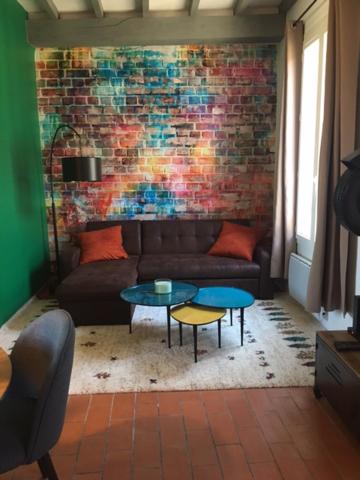 sala de estar con sofá y pared de ladrillo en Le Mondrian atypique Intra-Muros, en Aviñón