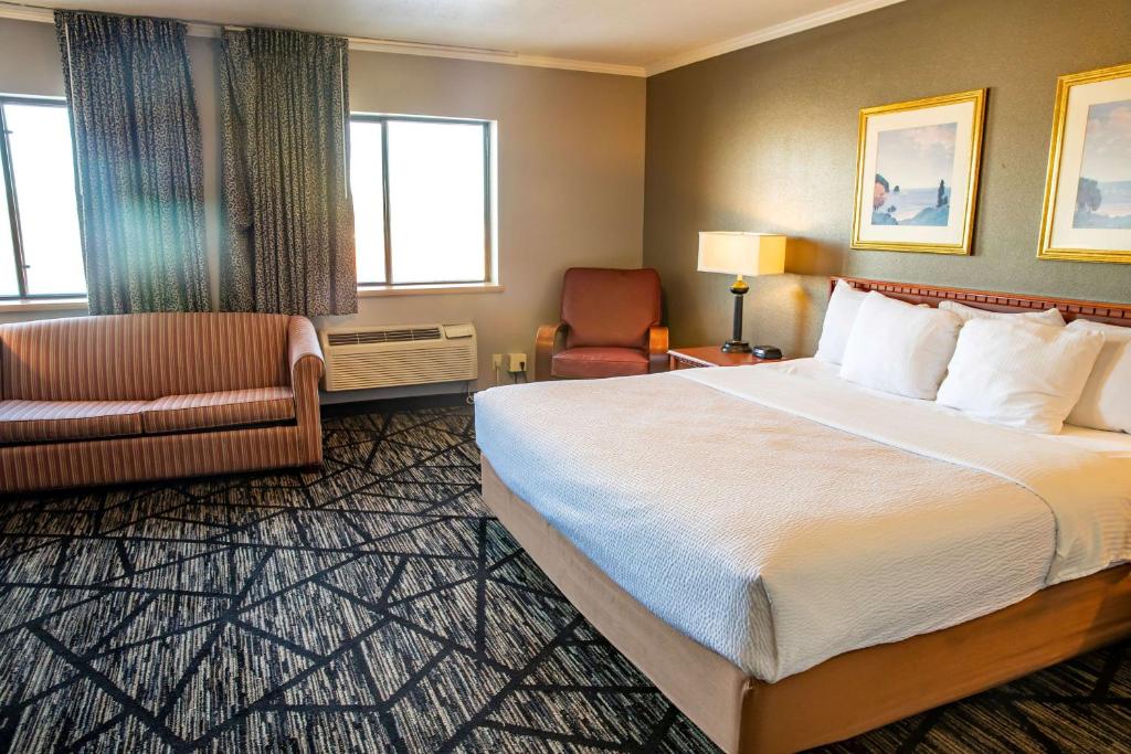 a hotel room with a large bed and a chair at La Quinta Inn by Wyndham Milwaukee Airport / Oak Creek in Oak Creek