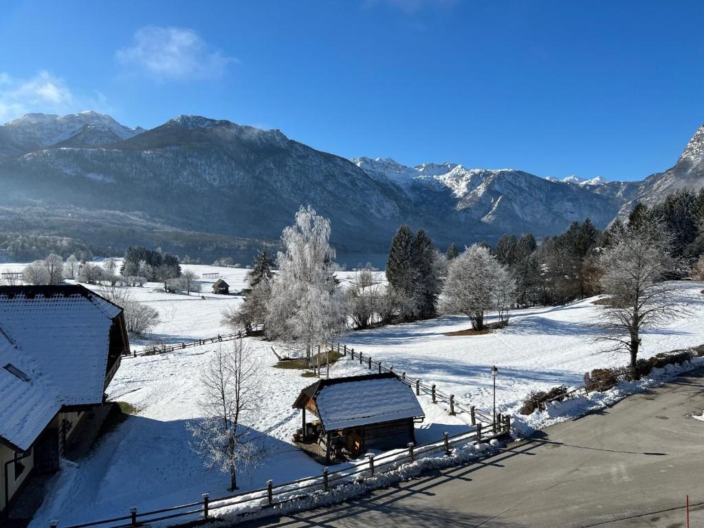 a snow covered field with a barn and a truck at Gloria Holiday - Apartment Bohinj in Bohinj