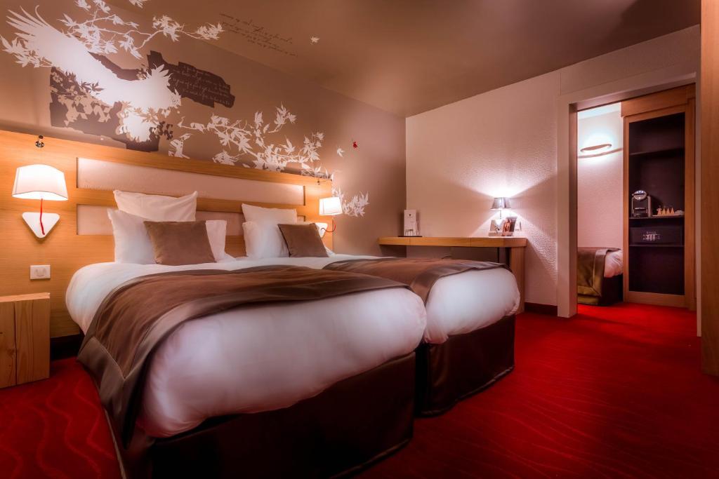 a hotel room with a large bed in a room at Le Grand Aigle Hotel & Spa**** in La Salle-les-Alpes