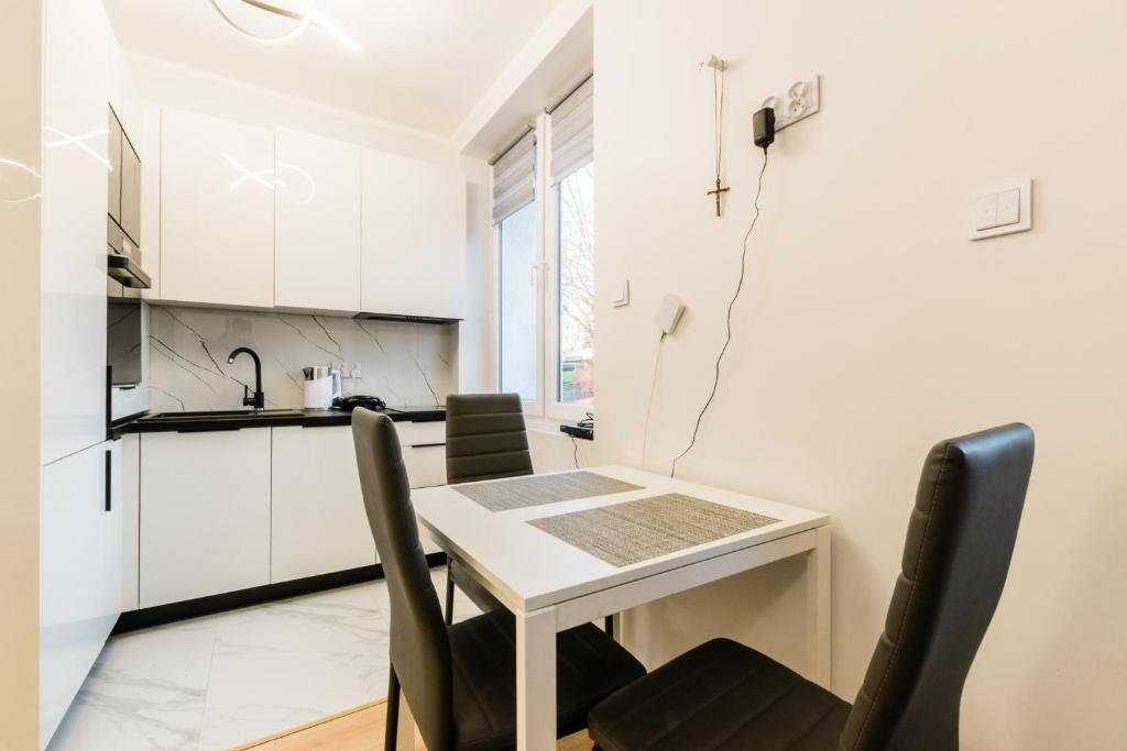 una pequeña cocina blanca con mesa y sillas en Apartament AC1 en Olsztyn