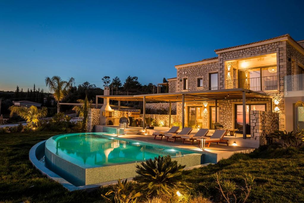 a house with a swimming pool in front of it at Zeus Exclusive Villas in Spartia